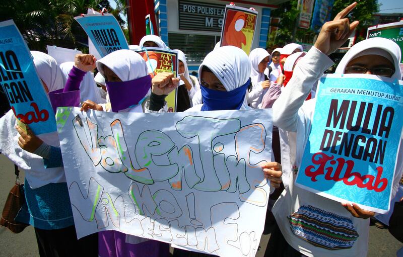 Indonesian Muslim women hold banners that read "Honourable by wearing veil" and "No Valentine's day" during a protest against Valentine's day in Malang, East Java on February 14, 2012.  Conservative Indonesian Islamic groups denounced Valentine's Day, saying it is un-Islamic, promoting promiscuity, casual sex and consumption of alcohol while other groups described the day as foreign cultural influence.    AFP PHOTO / AMAN ROCHMAN
 *** Local Caption ***  864288-01-08.jpg