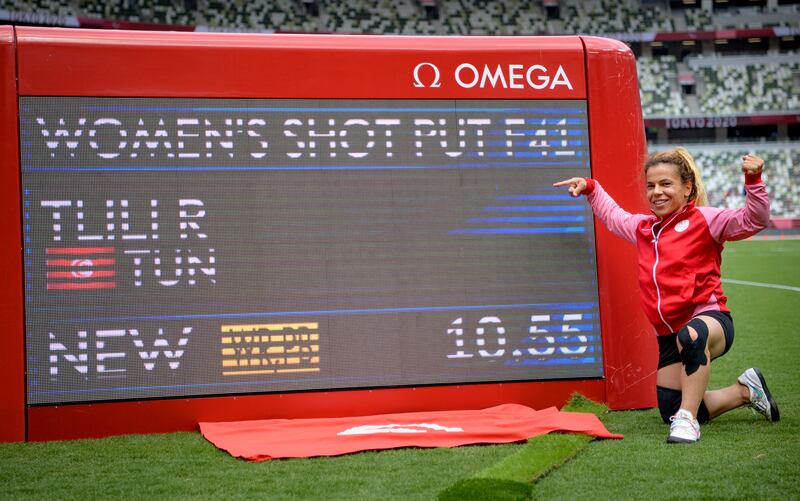Tunisia's Raoua Tlili poses next to the digital scoreboard showing her world record and winning throw in women's shot put F41.