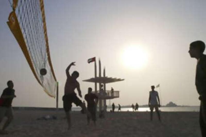 Young men play volleyball at sunset on the unrestricted section of Abu Dhabi Beach on the Corniche.