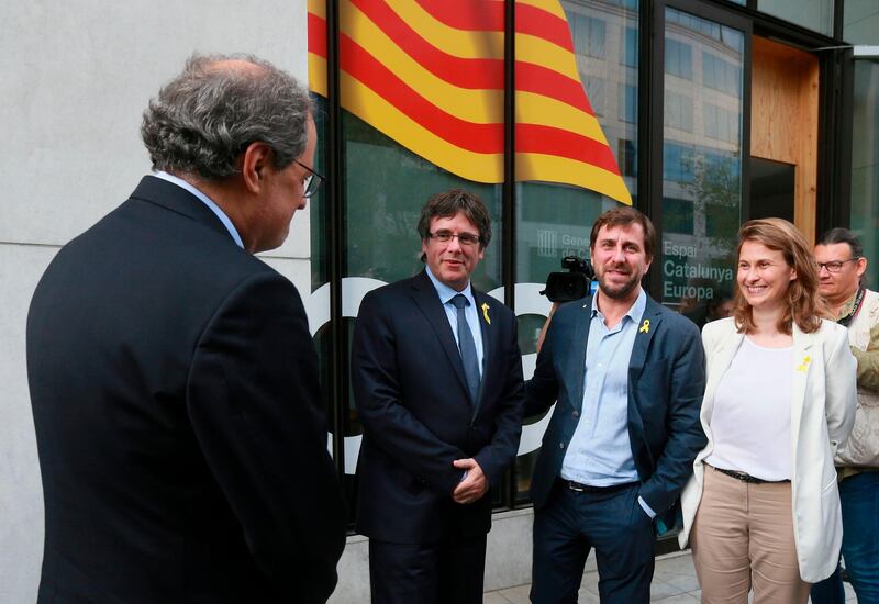 TOPSHOT - Catalonia's ousted regional president Carles Puigdemont (2L), flanked by former Catalan Health minister Antoni Comin (2R) and former Catalan Minister of Agriculture, Livestock, Fisheries and Food Meritxell Serret (R), looks at his designated successor, Catalan regional president Quim Torra (back) in Brussels on July 28, 2018 upon his arrival from Germany where he was detained at Madrid's request.  Catalonia's deposed president Carles Puigdemont has returned to Belgium on July 28 to keep pressing for his region's independence after a Spanish judge dropped a European arrest warrant for him. / AFP / JOHN THYS
