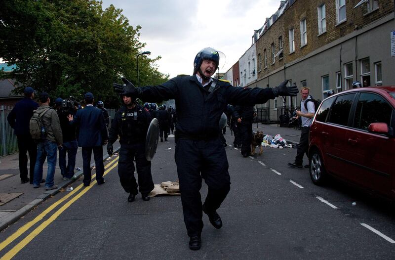A police officer pushes the media back during a police charge in Hackney, north London on 8 August 2011.  Now in it's third night of unrest, London has seen sporadic outbreaks of looting and clashes both north and south of the river Thames. Two police cars and a large number of buildings were on Saturday set ablaze in Tottenham, north London following a protest over the fatal shooting of a 29-year-old man in an armed stand-off with officers.  The patrol cars were torched as dozens gathered outside the police station on the High Road in Tottenham. AFP PHOTO / LEON NEAL
 *** Local Caption ***  575769-01-08.jpg