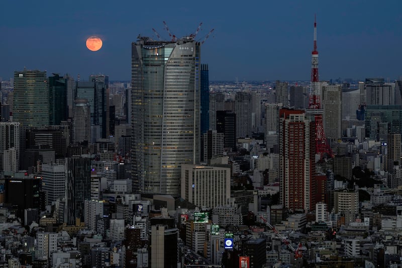 A full moon rises above the Tokyo skyline. Photo: AP