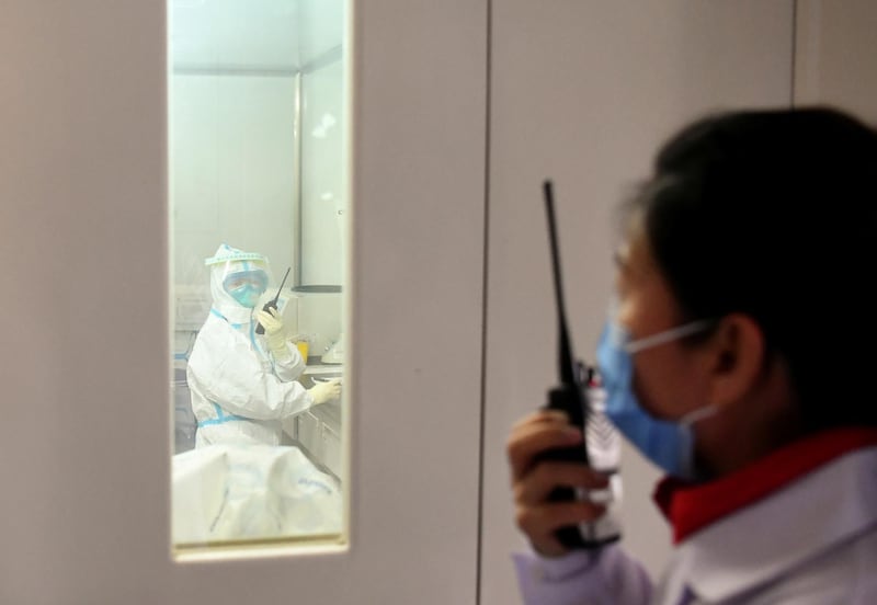 A member of a coronavirus prevention and control team communicates through walkie-talkie with a colleague inside a laboratory at the Ningxia Center for Diseases Prevention and Control in Yinchuan, Ningxia Hui Autonomous Region, China. Reuters