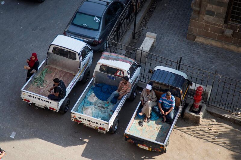 Drivers rest on their vehicles parked on a street in Old Cairo, Egypt.  EPA
