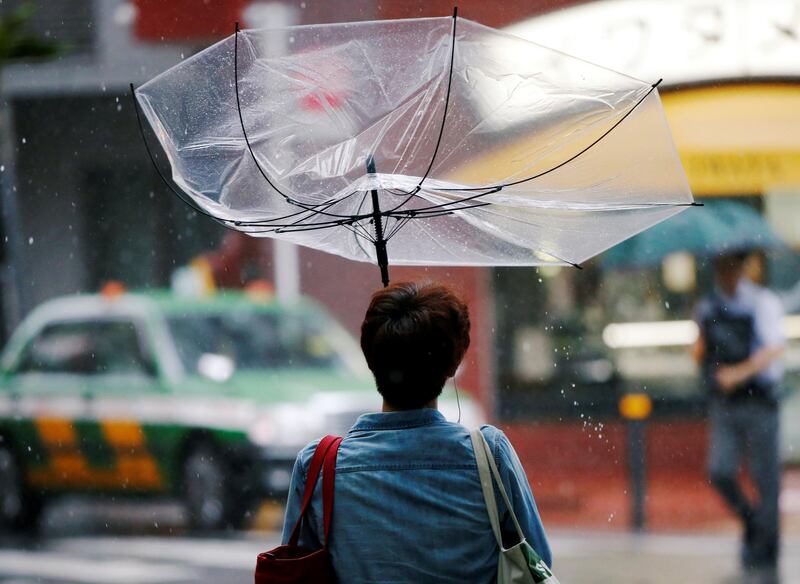 A passerby using an umbrella struggles against a heavy rain and wind as Typhoon Jongdari approaches Japan's mainland in Tokyo, Japan July 28, 2018. REUTERS / Issei Kato