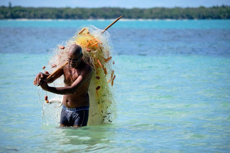 A fisherman carries a net to catch mullet in the bay of Saint-Maurice, on the Iles Des Pins, in the French Pacific territory of New Caledonia. AFP
