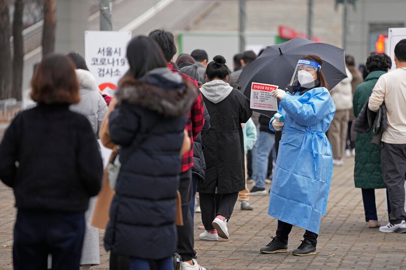 A medical worker holds a sign for visitors to prepare for coronavirus tests at a temporary screening clinic in Seoul, South Korea. AP
