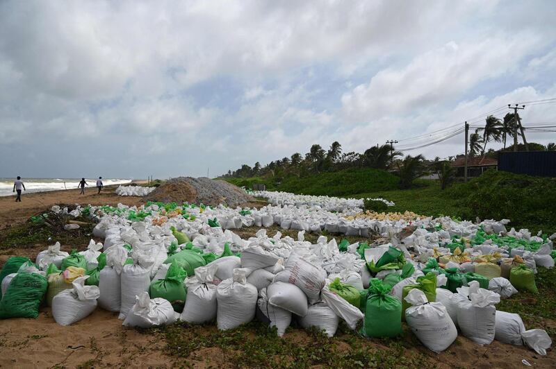 Members of Sri Lankan Navy walk past the stacked sacks filled with debris washed ashore from the Singapore-registered container ship 'MV X-Press Pearl'. AFP