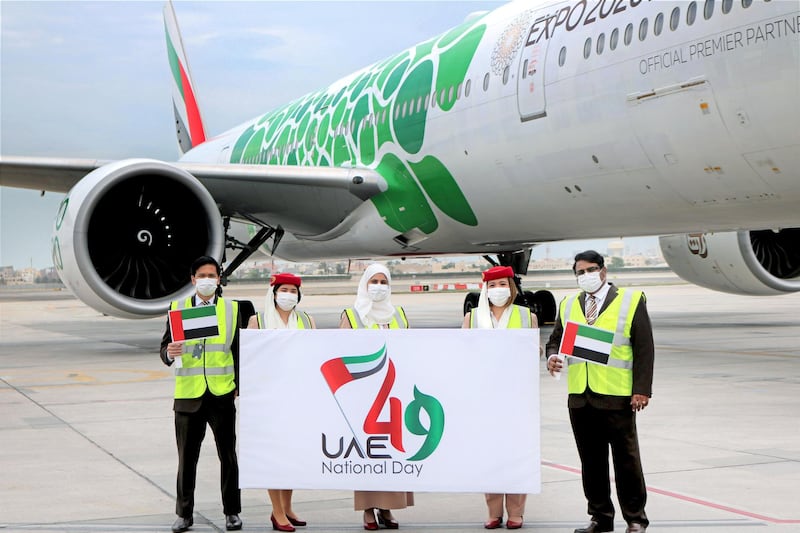 Emirates staff in Bahrain send National Day greetings in front of jet with green Expo2020 Dubai livery. 