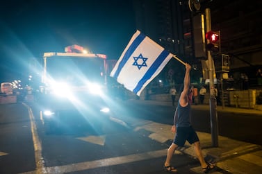 A protester waves the Israeli flag as he walks in front of a police water cannon truck during a demonstration on Saturday. Getty