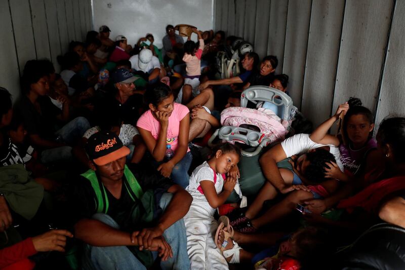 Migrants, part of a caravan traveling to the United States, sit in the back of a truck, as they hitch a ride near Sayula de Aleman, Mexico. Reuters