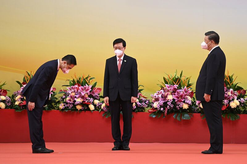 Hong Kong's new Secretary for Innovation, Technology and Industry Sun Dong, left, bows as Mr Xi and Mr Lee look on. AP