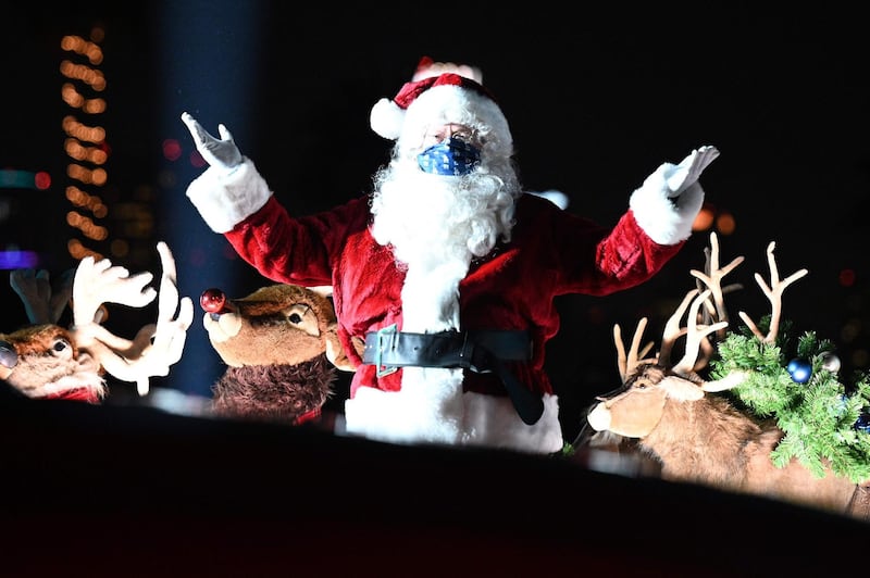 Santa Claus gestures to visitors in their cars as they attend the Dodgers Holiday Festival, a drive-thru light and performance experience in Los Angeles, California. AFP