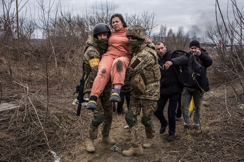 Ukrainian soldiers carry a woman fleeing the town of Irpin. AP
