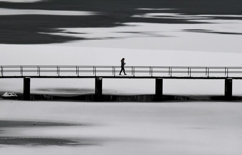 A pedestrian walks on a bridge over Lake Eibsee, southern Germany. Christof Stache / AFP Photo