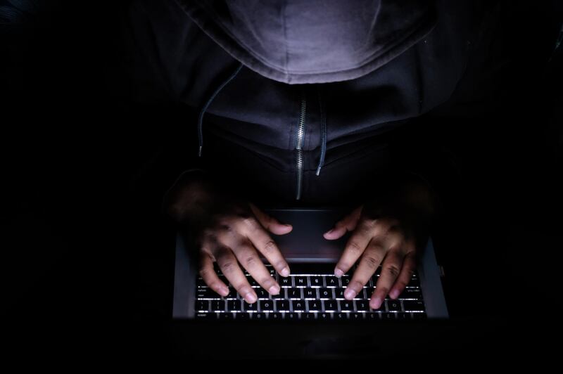 Man behind laptop, man hacker, laptop on desk. Getty Images