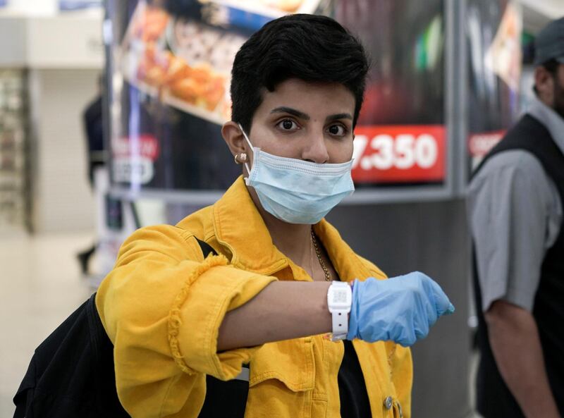 A Kuwaiti woman wearing a protective face mask poses as she shows her quarantine tracking bracelet upon her arrival from Amman to Kuwait Airport.  Reuters