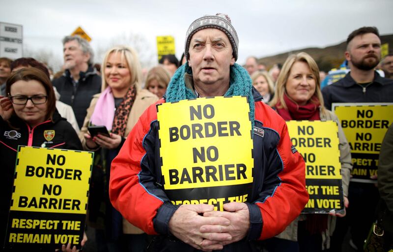 Protesters against any border between Ireland and Northern Ireland because of Brexit hold placards at the Carrickcarnan border between Newry in Norther Ireland and Dundalk in the Irish Republic on March 30, 2019.  British Prime Minister Theresa May on Saturday mulled a possible fourth attempt to get her Brexit agreement through parliament, faced with the growing risk of a chaotic no-deal exit in less than two weeks' time. Britain's exit from the European Union brings with it the fear of the possible reimposition of physical checks on the Irish border, which would be the UK's only land border with the EU, a fear especially real in a no-deal scenario. A so-called hard border could threaten the 1998 Good Friday Agreement that brought an end to decades of civil strife between Protestant supporters of British rule over the province, and Irish Catholic nationalists, who believe in a united Ireland. / AFP / Paul FAITH
