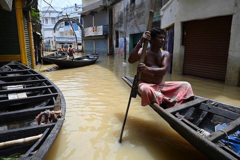 A resident rides a boat along a road submerged by floodwaters following heavy monsoon rains in Ghatal, Paschim Medinipur district, India.