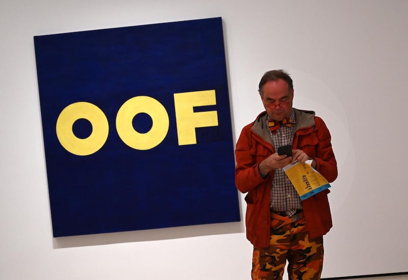 A member of the media stands next to Edward Ruscha's "OOF."
