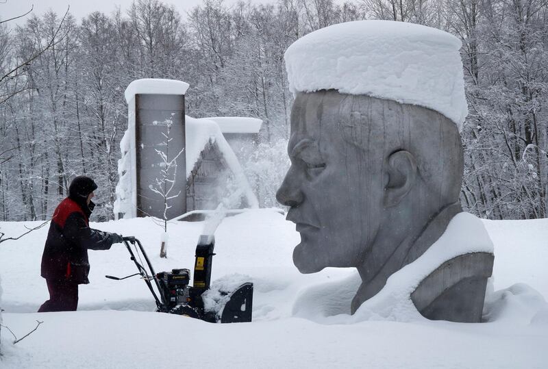 A worker clears snow next to the statue of Vladimir Lenin outside St Petersburg, Russia. AP Photo