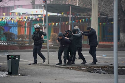A police officer escorts a group of detained protesters in Almaty, Kazakhstan, Thursday, Jan.  6, 2022.  Vladimir Tretyakov/NUR. KZ via AP