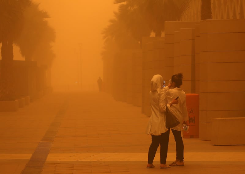 Women film the storm in Kuwait City. AFP