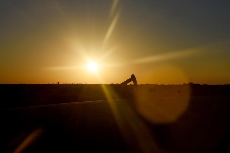 The sun sets behind an oil rig seen from Monahans Sandhills State Park in Monahans, Texas, U.S., on Tuesday, June 19, 2018. In the West Texas plains, frack-sand mines suddenly seem to be popping up everywhere. Twelve months ago, none of them existed - together, these mines will ship some 22 million tons of sand this year to shale drillers in the Permian Basin, the hottest oil patch on Earth. Photographer: Callaghan O'Hare/Bloomberg