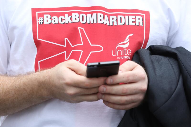 A demonstrator uses his mobile phone as workers, union representatives and supporters protest in support of Bombardier Inc. workers outside the Houses of Parliament in London, U.K., on Wednesday, Oct. 11, 2017. As if Brexit weren���t enough, Prime Minister��Theresa May��is fighting on two fronts to protect jobs across the U.K. after��BAE Systems Plc announced cuts and a dispute between��Bombardier��Inc.��and��Boeing Co.��festers. Photographer: Luke MacGregor/Bloomberg