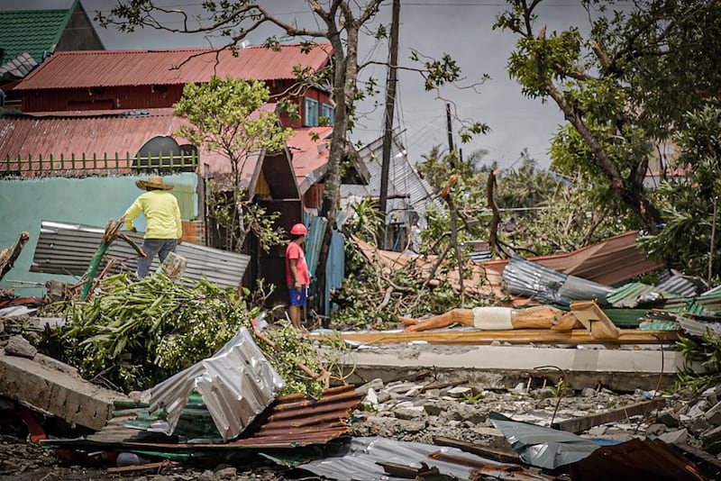 Residents stand amongst debris and next to a huge crucifix blown from the church after it was destroyed at the height of Typhoon Vongfong in Arteche town, Eastern Samar province. AFP