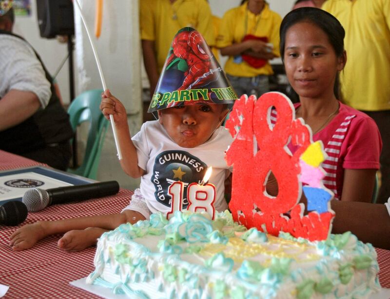 Junrey Balawing, center, blows a candle as he celebrates his 18th birthday after being declared 'the world's shortest living man' by the Guinness World Records adjudicator Craig Glenday in ceremony at Sindangan Municipal Hall, Sindangan township, Zamboanga Del Norte province in Southern Philippines, Sunday June 12, 2011 which is coincidentally the Philippines' Independence Day. Balawing was officially declared 'the world's shortest living man' with a measurement of 23.5 inches (59.93 centimeters) dislodging Nepal's Khagendra Thapa Magar with a measurement of 26.4 inches. Behind is Balawing's sister Giselle.(AP Photo/Bullit Marquez) *** Local Caption ***  XBM106_Philippines_Shortest_Man.jpg