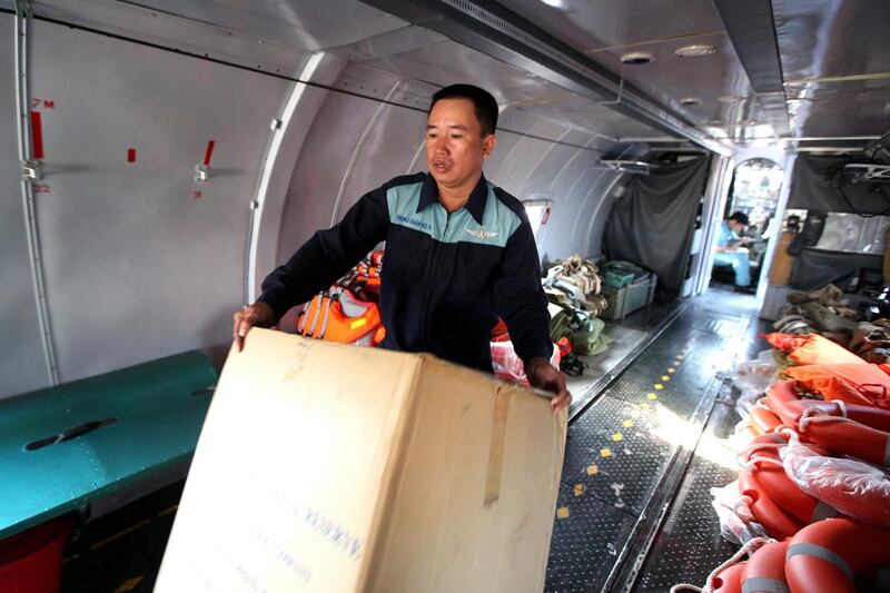 An official carries a box of life jackets inside a Vietnamese Air Force plane. Luong Thai Linh / EPA March 10