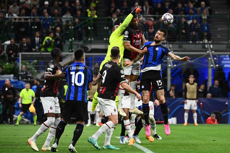 AC Milan goalkeeper Mike Maignan jumps for the ball under pressure. AFP
