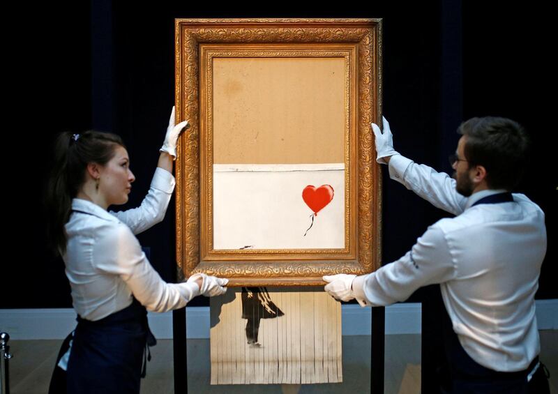 Staff from Sotheby's auctioneers reposition Banksy’s Love is in the Bin, which is now half-shredded, in London, Britain, October 12, 2018. REUTERS/Henry Nicholls  -  ATTENTION EDITORS  - FOR EDITORIAL USE ONLY. NO RESALES. NO ARCHIVES.