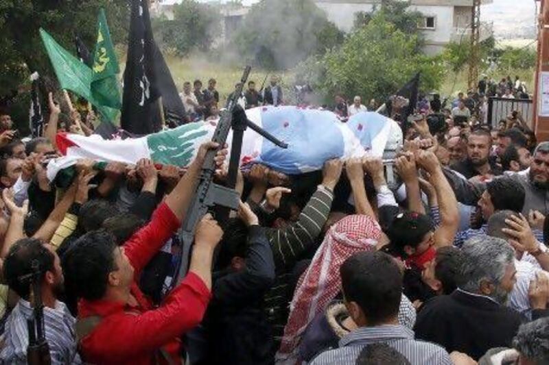 Crowds of mourners and gunmen carry the body of Sheikh Ahmed Abdul Wahid, a Sunni Muslim cleric, during his funeral at his hometown at Al Bireh, north Lebanon, yesterday.