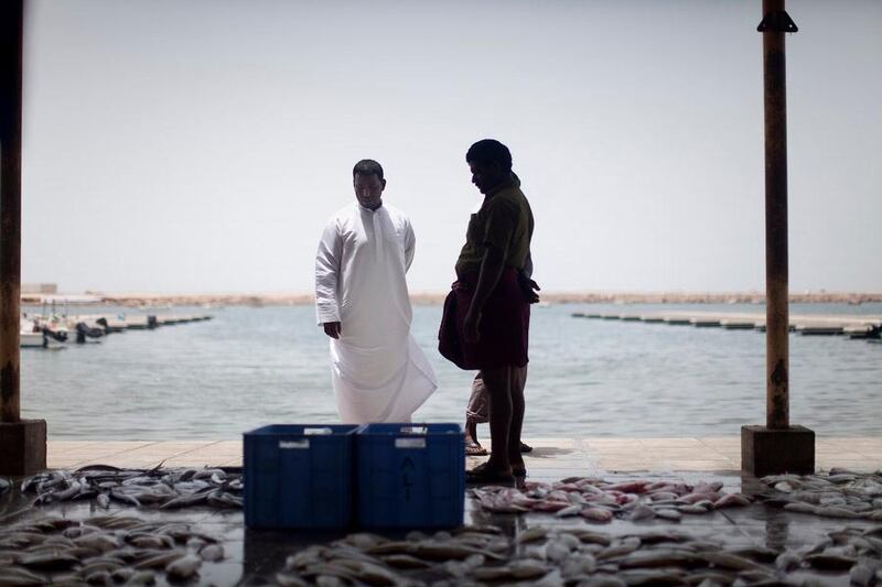 Ras Al Khaimah, July 13, 2011:

With the new corniche complete, much of the city has migrated its attention over there, at least in the winter months. But the old industry still breathes life that its newer counterpart cannot during the sumertime. Why? Because it has industry. Here a local fisher shows his catches to a prospective customer. Though vanishing the old part of RAK city is still intact, for the time being. 

Lee Hoagland/The National