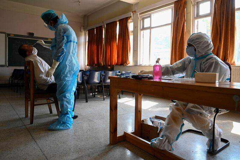 A medical worker collects a swab sample from a staff member of the Burnhall school inside a classroom for a Rapid Antigen Test (RAT) for the Covid-19 coronavirus, in Srinagar. AFP
