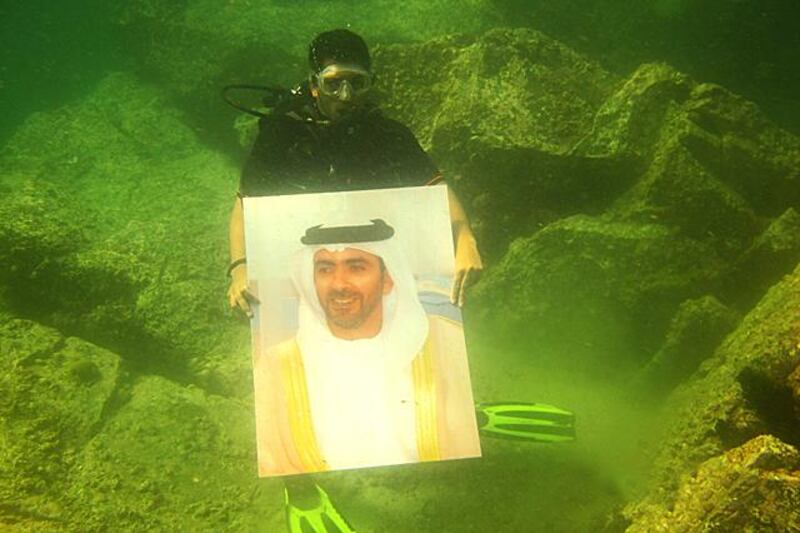 a diver from EIDA with a picture of Lt General Sheikh Saif bin Zayed, Deputy Prime Minister and Interior Minister, and Vice Chairman of EIDA underwater at marine sanctuary in the Emirate of Ajman