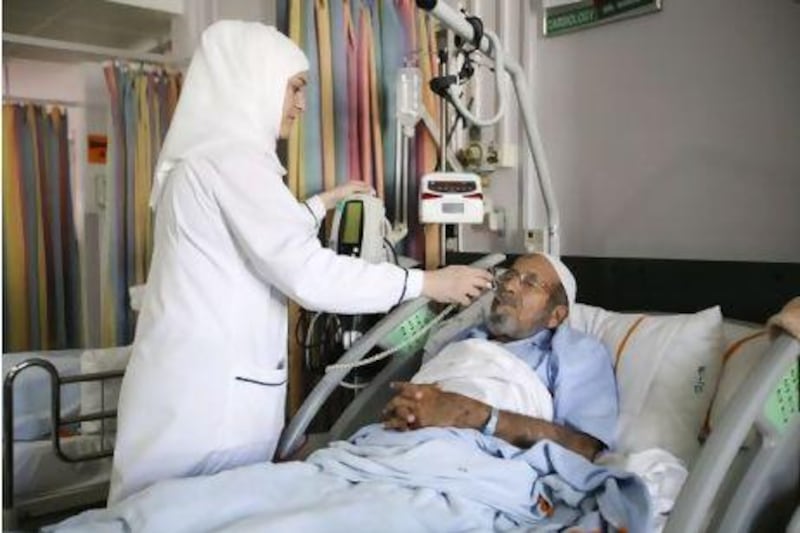 November 29, 2011, Dubai, UAE: Right to left: Hind Mahmoud Abdulla Younes,is a nurse in the Trauma center of Rashid hospital. She takes care of multiple patients in severe pain, 12 hours at a time.  Here she takes the temperature of Mohammed Nasser who suffers from a cervical disc prolapse.  Lee Hoagland/The National