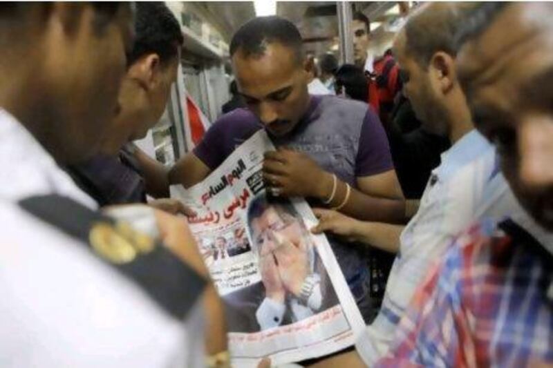 Egyptians read a newspaper featuring their newly elected president Mohammed Morsi in Cairo. Mr Morsi started work on forming a government yesterday even before he had a clear picture of what he could do after the ruling military stripped most of the powers from his post.