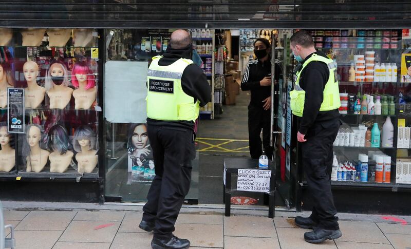 Redbridge enforcement officers close a click and collect shop in the town centre of Ilford. AP Photo