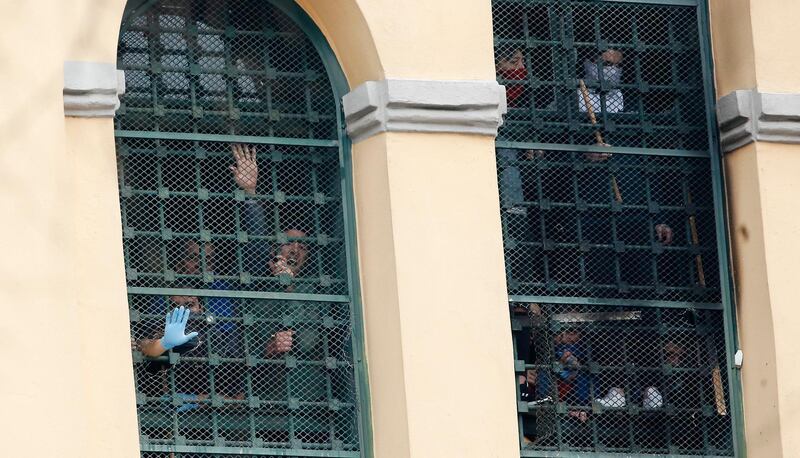 Inmates stand behind bars at the San Vittore prison as protests broke out following restrictions that were imposed on family visits to prevent coronavirus transmissions, in Milan, Italy. AP Photo