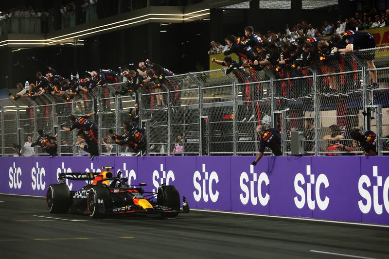 Refd Bull's race winner Sergio Perez passes his team celebrating on the pitwall. Getty