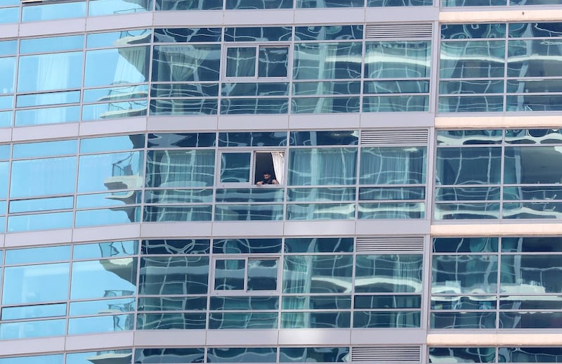 DUBAI, UNITED ARAB EMIRATES , April 17– 2020 :- One of the resident looks out from his apartment in Dubai Marina in Dubai. Dubai is conducting 24 hours sterilisation programme across all areas and communities in the Emirate and told residents to stay at home. UAE government told residents to wear face mask and gloves all the times outside the home whether they are showing symptoms of Covid-19 or not.  (Pawan Singh / The National) For News/Online/Instagram
