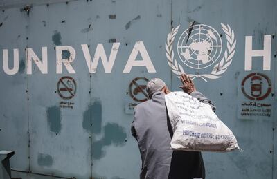 A Palestinian man stands in front of the emblem of the UN Relief and Works Agency for Palestine Refugees in the Near East (UNRWA) outside the agency's offices in Gaza City on July 31, 2018. / AFP PHOTO / SAID KHATIB