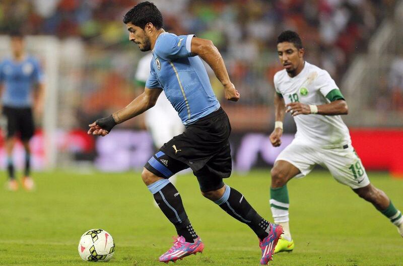 Luis Suarez dribbles as he gets chased down by Salem Al Dawsari during an international friendly against Saudi Arabia in Jeddah on Friday. AFP Photo / October 10, 2014