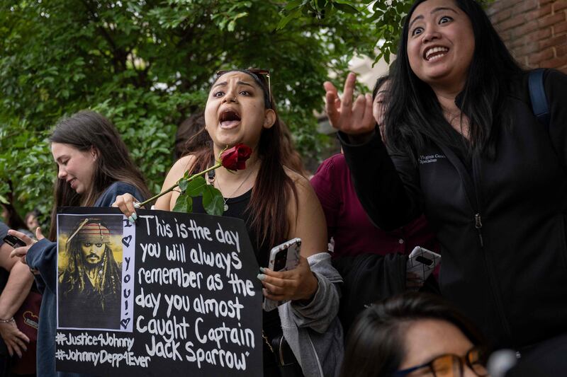 Fans of Depp shout at a supporter of Heard. AFP