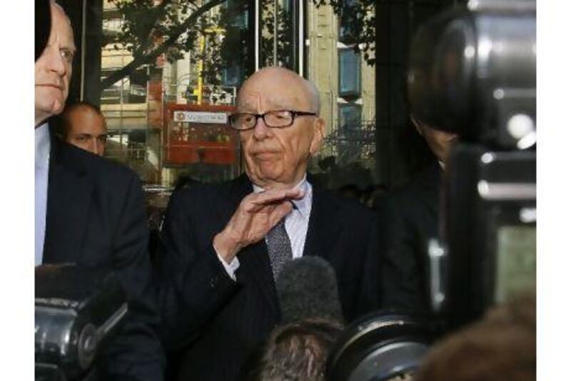 Rupert Murdoch, centre, attempts to speak to the media after he held a meeting with the parents and sister of murdered school girl Milly Dowler in London on Friday. The lawyer for Milly Dowler's family says Rupert Murdoch has issued a full and sincere apology to the murdered schoolgirl's family for the actions of journalists at his newspaper. Kirsty Wigglesworth / AP Photo