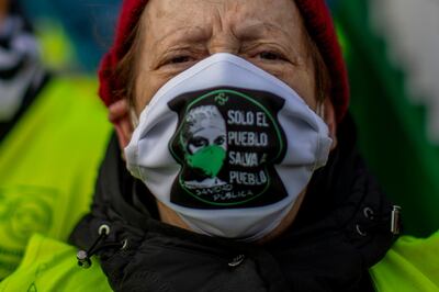 A woman wearing a face mask reading in Spanish: "Only the people can save the people" protests against plans by Madrid's authorities to force staff to transfer to other hospitals at the 12 Octubre hospital in Madrid, Spain, Friday, Dec. 11, 2020. The rate of Spain's coronavirus contagion has dropped to levels not seen since the end of August, when a resurgence began in earnest, but the country's top coronavirus expert says that the situation remains of "high risk" and that the curve of contagion needs to be flattened to avoid a third wave before vaccination begins. (AP Photo/Manu Fernandez)