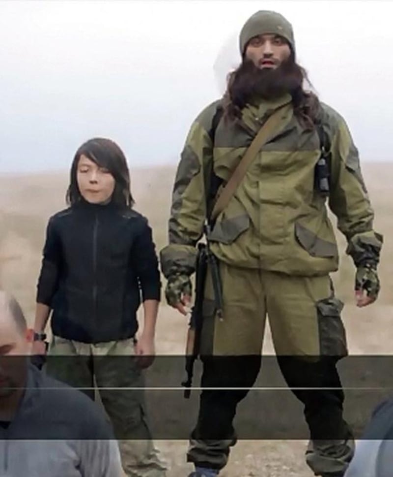 An image grab taken from a video reportedly taken on November 24, 2014 allegedly shows an ISIL fighter speaking to the camera next to a child, who is identified in an earlier propaganda video as Abdullah from Kazakhstan, before the child executes two men. Al Hayat Media Centre/AFP Photo/Handout


